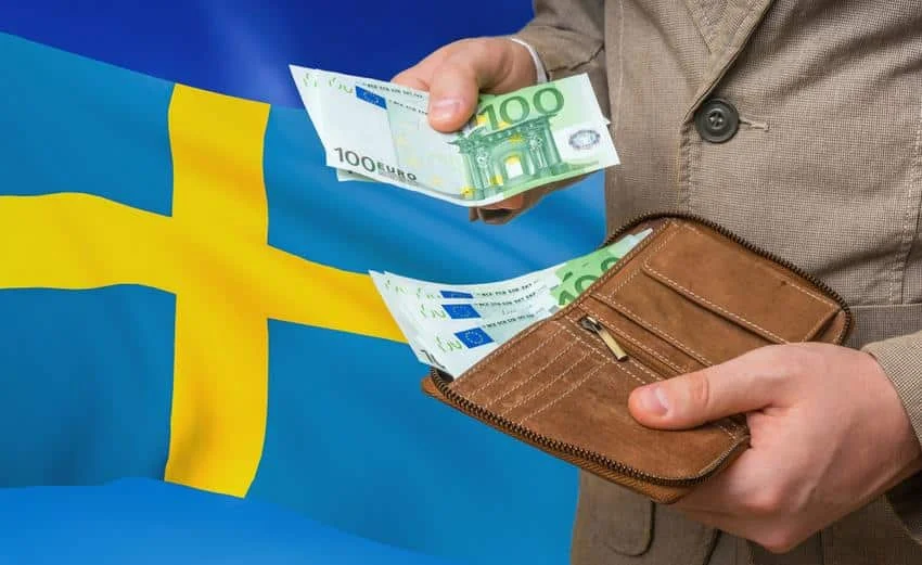 Svenska flaggan med en man som tar ut svenska sedlar från sin plånbok för att betala.